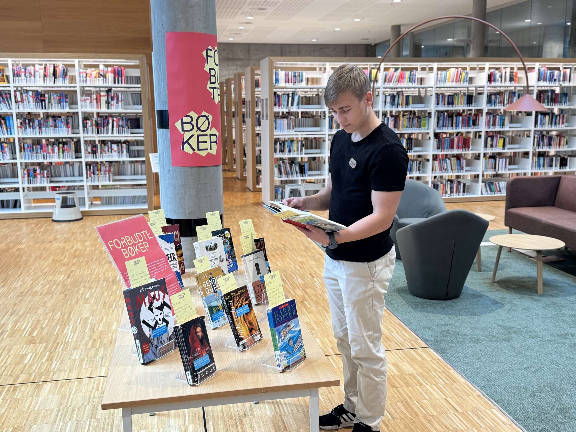 En person kikker i en bok ved utstillingen om forbudte bøker