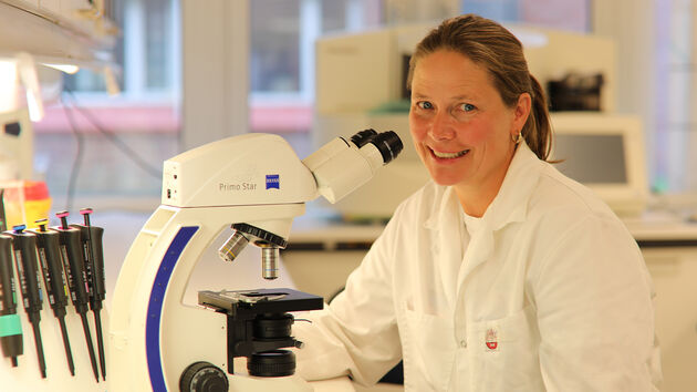 Bilet viser cellebiolog Nina Marie Pedersen avbildet ved et mikroskop på laboratoriet. 