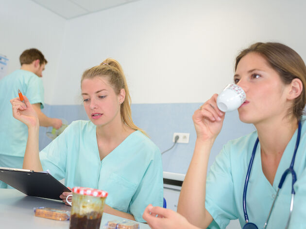 Bildet viser sykepleiere som sitter ved et bord og en sykepleier stående i bakgrunnen.