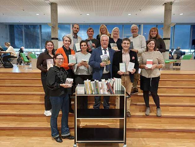 gruppe mennesker oppstilt i trapp med en bok hver i hendene