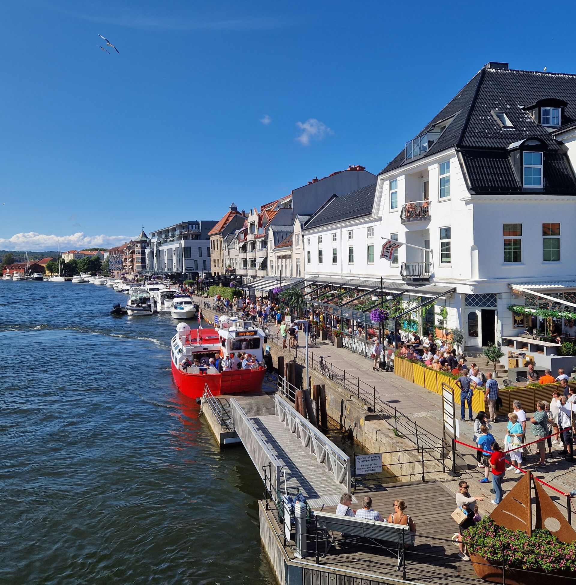 Foto av Fredrikstad by, langs vannet med ferja i bakgrunnen. 