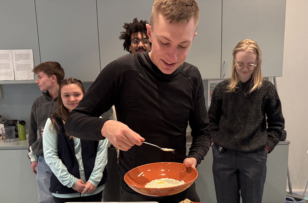 Bildet viser en student som forsyner seg med julegrøt. I bakgrunnen fire andre studenter. 