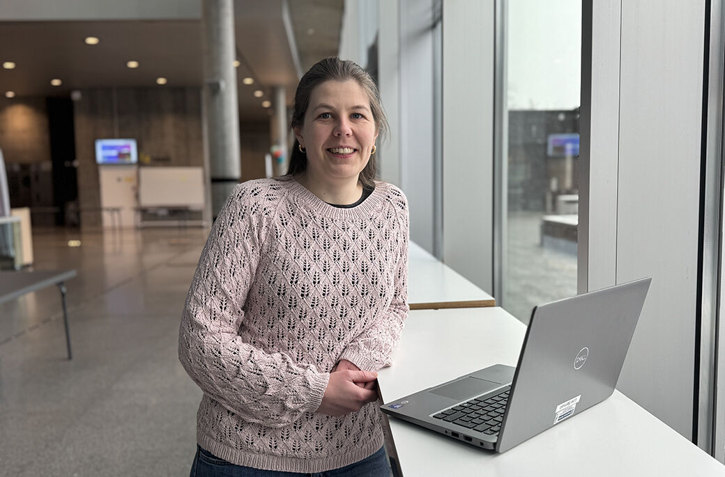 Bilde viser forskeren avbildet foran en pc i et fellesområde på høgskolens campus.