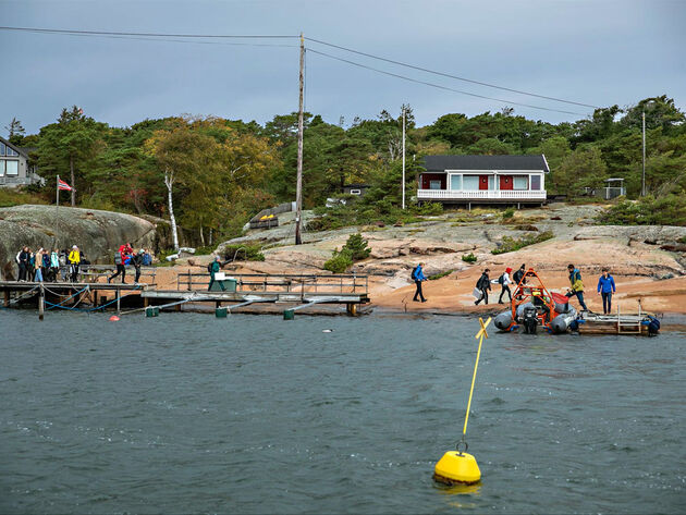 Bilde viser en gruppe mennesker på tur i strandkanten. 