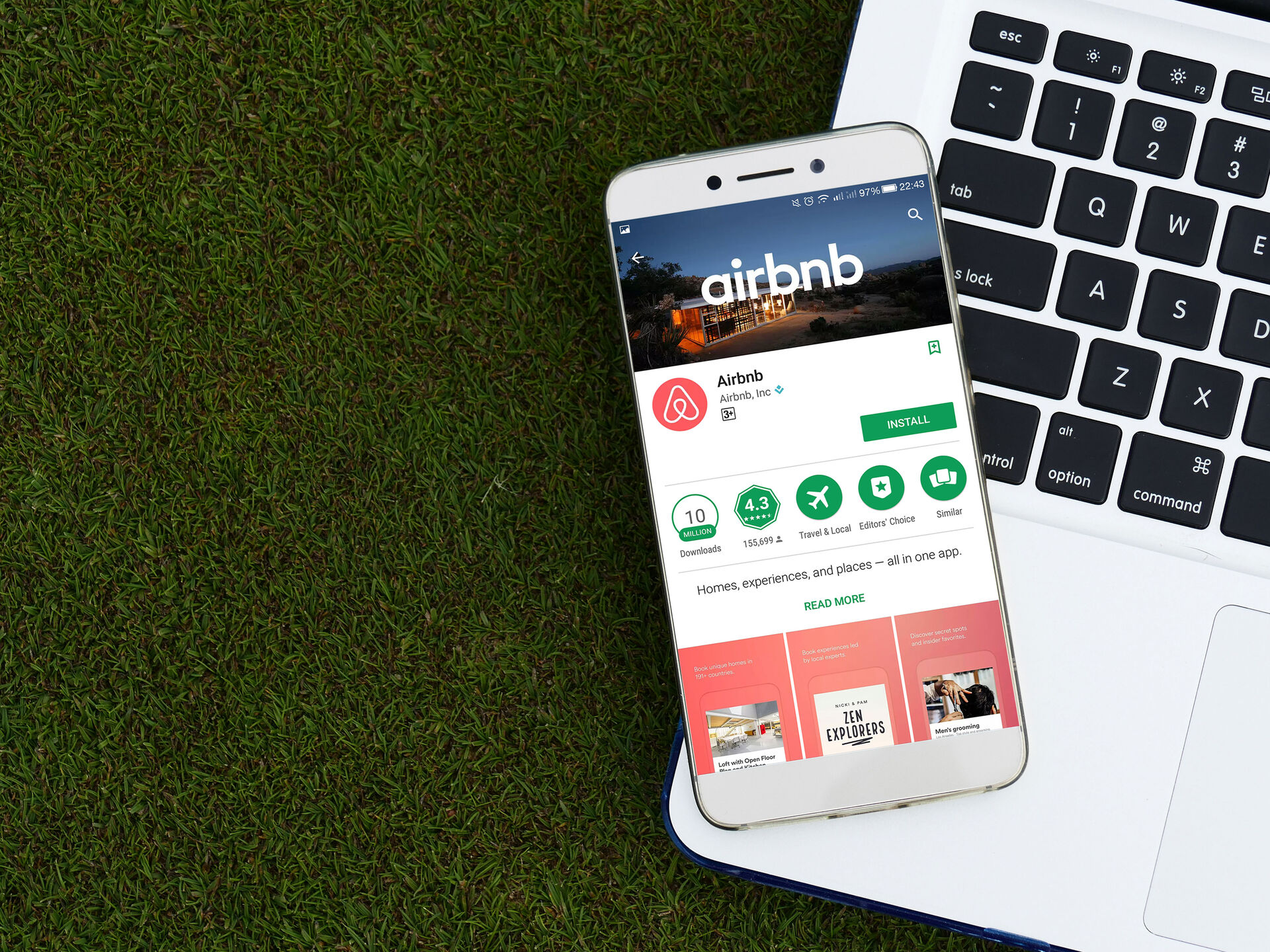 Airbnb's main webpage displayed on a smartphone that lies on a laptop