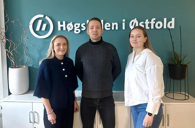 Bildet viser de tre innovasjonsstudentene med navnet og logoen til Høgskolen i Østfold i bakgrunnen. 