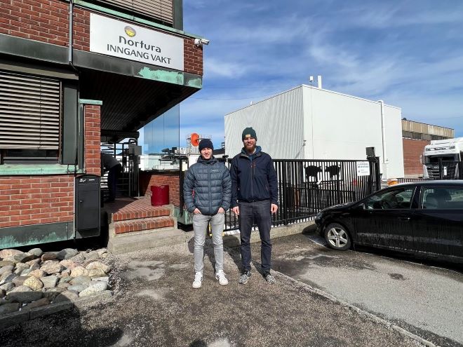 Gruppebilde viser bachelorgruppen foran Nortura sin fabrikk i Sarpsborg, Simen Iversen til venstre og Simen-O. Kobbevik til høyre.