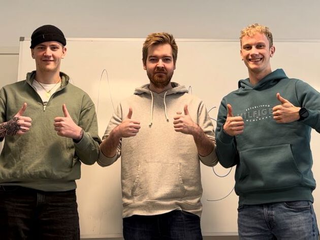 De tre studentene står på rekke og viser tommel opp med hendene.