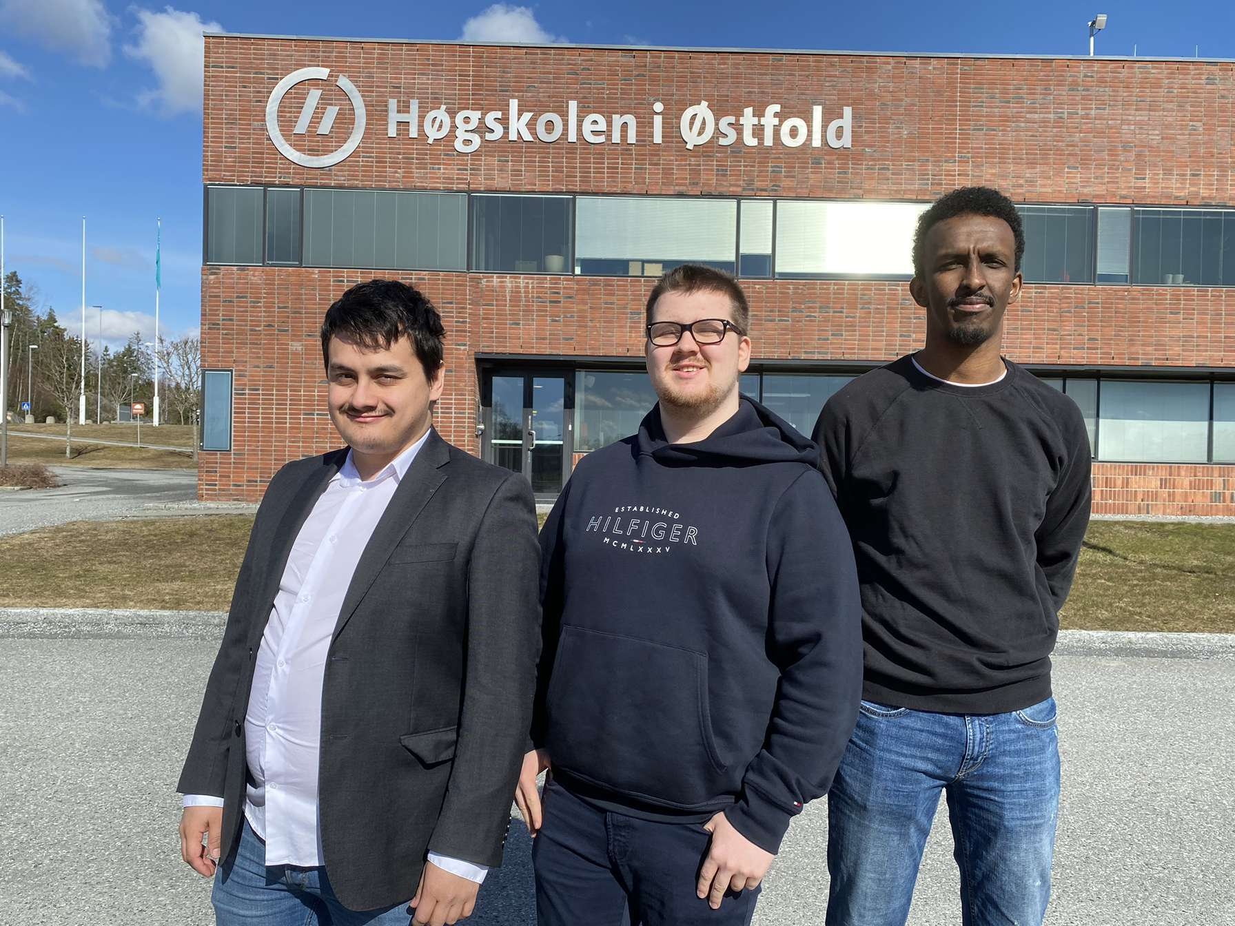 De tre prosjektdeltakerne Anders Camilo Grindal, Herman Kristiansen og Mohamed Abdi Mohamud står på rekke foran campus Remmen.