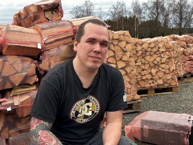 Joachim Randa sitter på huk foran stabler med ved.