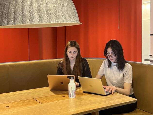 The two students, Héliade and Nada, sits in front of their lap top. 