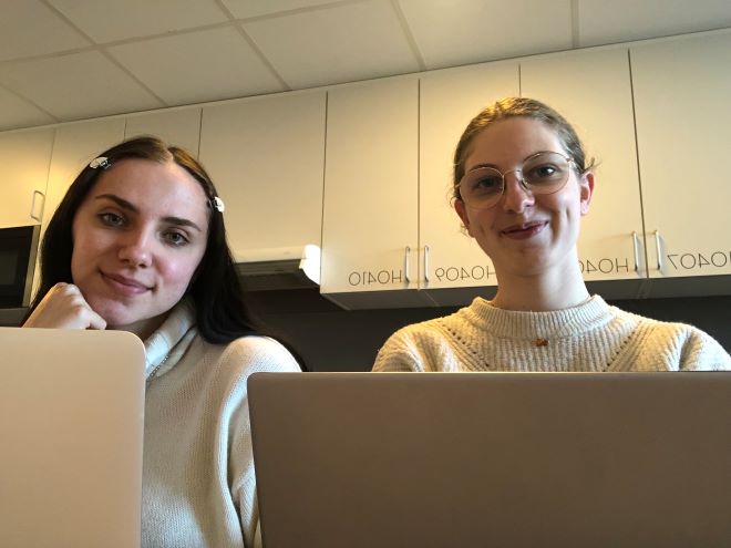 Betty Malot and Elise Moreau sits in front of a laptop. 