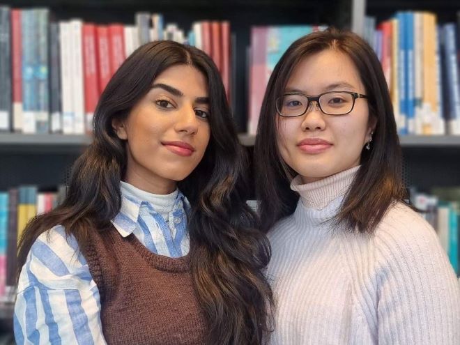 De to prosjektdeltakerne Zainab og Nhu-Phung står foran en bokhylle.