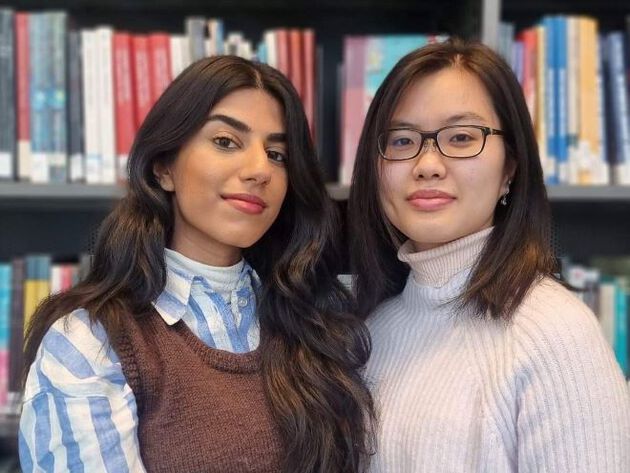 De to prosjektdeltakerne Zainab og Nhu-Phung står foran en bokhylle.