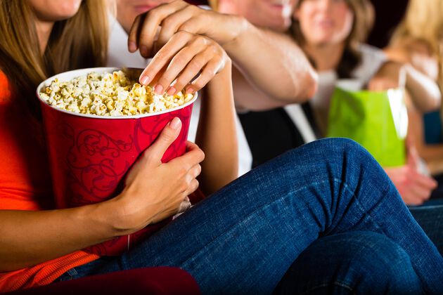 Nærbilde av folk i kinosal med popcorn. Foto. 