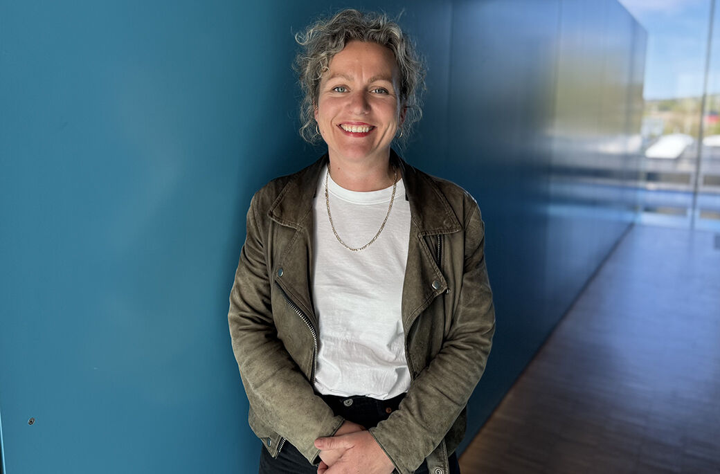 Bilde av Veslemøy Maria Fossum Johansson, doktorgradsstipendiat  i en av høgskolens blå korridorer på campus i Halden. 