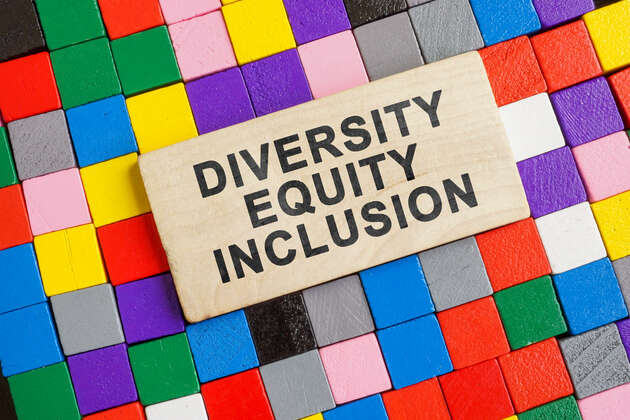 Et bilde av en plakett det står: "Diversity, Equity og Inclusion". Bak plaketten er det firkanter i ulike farger