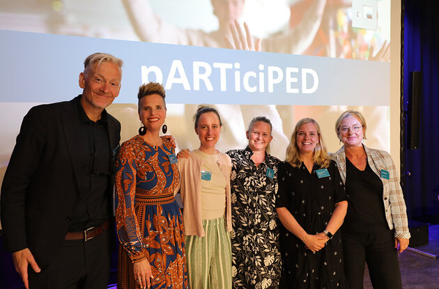 Seks av deltakerne i forskningsprosjektet avbildet på scenen under sluttkonferansen med navnet til prosjektet på lysbilde i bakgrunnen.  