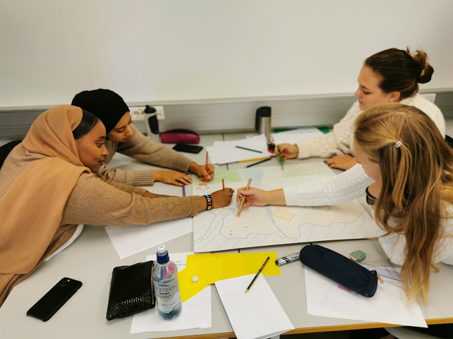 Her ses fire studenter som sitter rundt et bord og lager kart over sin del av øya. Foto: Kristine Høeg Karlsen