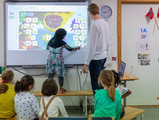 Bildet viser barneskoleelever og lærer i arbeid foran tavle i klasserom. 