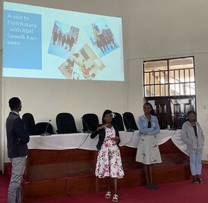 Biletet viser fire studenter som står framfor ein presentasjon på veggen.