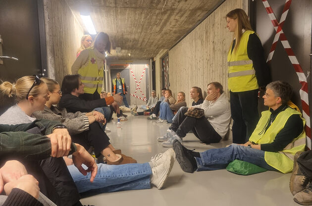 Bilde viser to lærerstudenter i samtale i klasserom foran en modell av et mikrosamfunn som er laget i en pallekasse. 