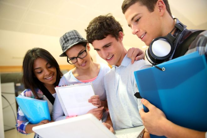 Bildet viser fire studenter som ser på en laptop.