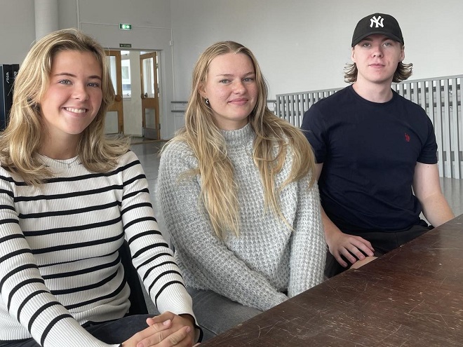 Tre studenter sitter ved et bord. 