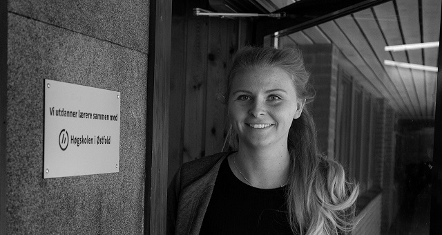 Bildet viser en kvinnelig lærerstudent som står i inngangen til en av våre praksisskoler. På skiltet ved siden av døra står det "Vi utdanner lærere i samarbeid med Høgskolen i Østfold".