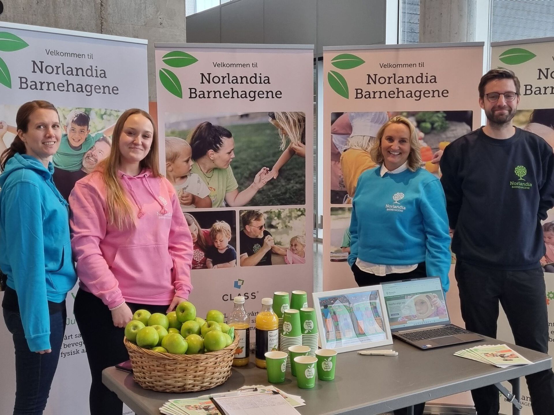 Fire ansatte ved Norlandia barnehagene står foran rolluper, som viser aktiviteten i virksomheten. 