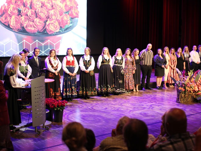 En rekke av grunnskolelærerstudenter står på scenen på avgangsseremonien, for å motta velfortjent hyllest. 