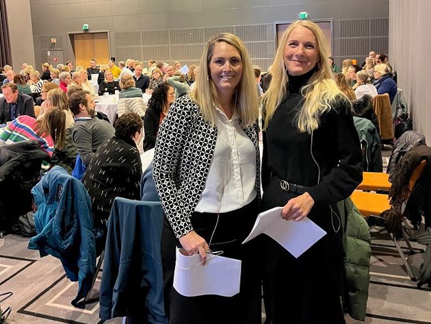 Vernica Knigge og Lin Ramberg står i konferansesalen under Praksiskonferansen 2023.