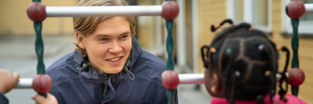 En mannlig student ser på en liten jente, som vi ser bakhodet til
