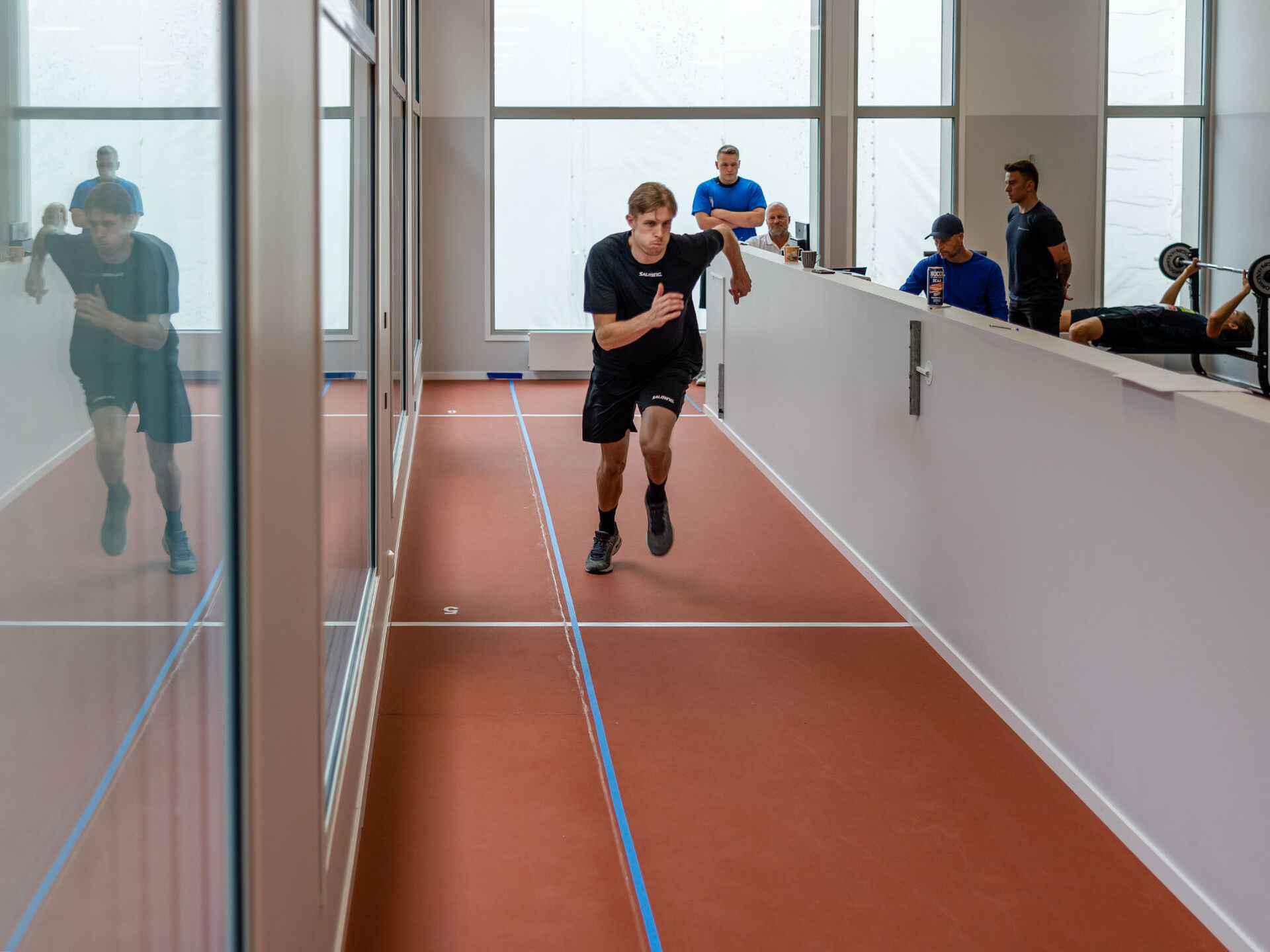 Bildet viser idrettsutøver som spurter på en bane i ny testlab i Fredrikstad, hvor tidtakerstreker er merket hver 5. meter