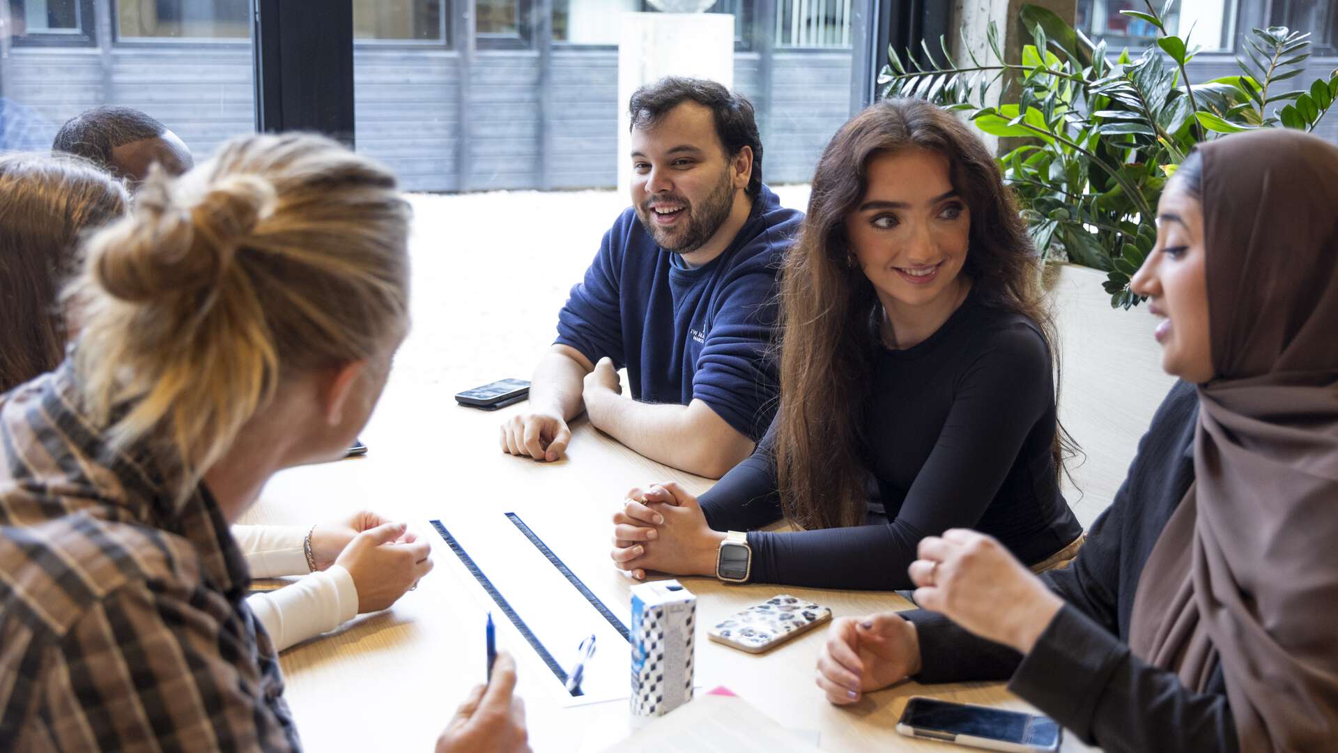 Studenter som sitter rundt et bord og diskuterer