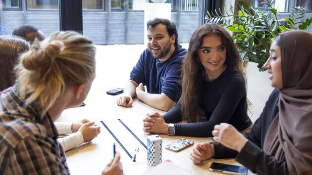 Studenter som sitter rundt et bord og diskuterer