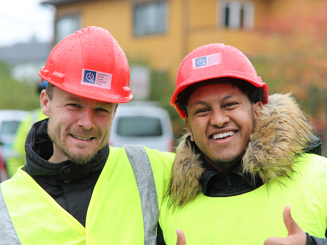 To smilende, mannlige studenter som gir tommel opp ute på befaringsstedet. Foto.