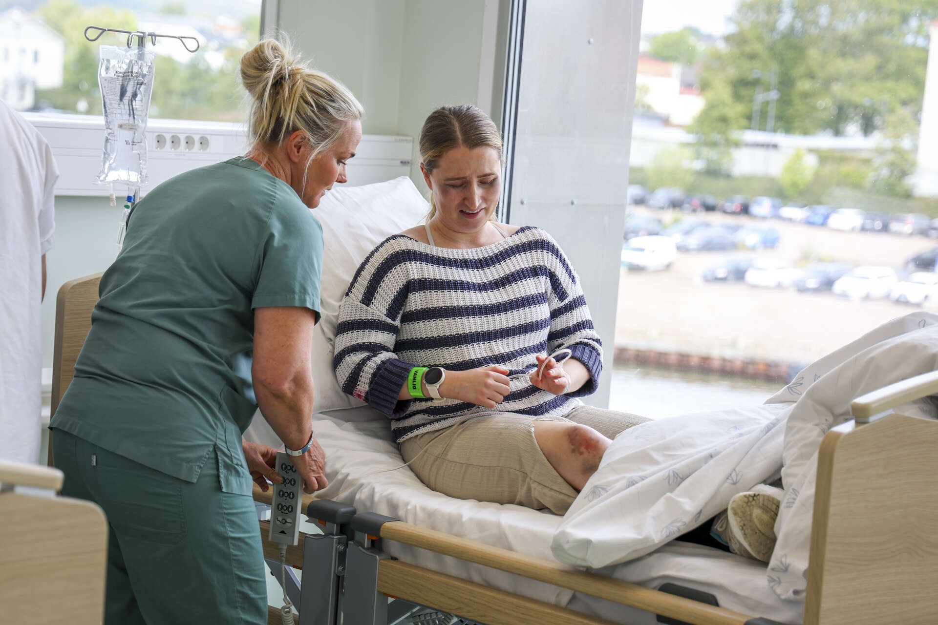 En sykepleier i samtale med en skadet "pasient" på båre, med sminke for å simulere skader. Foto.