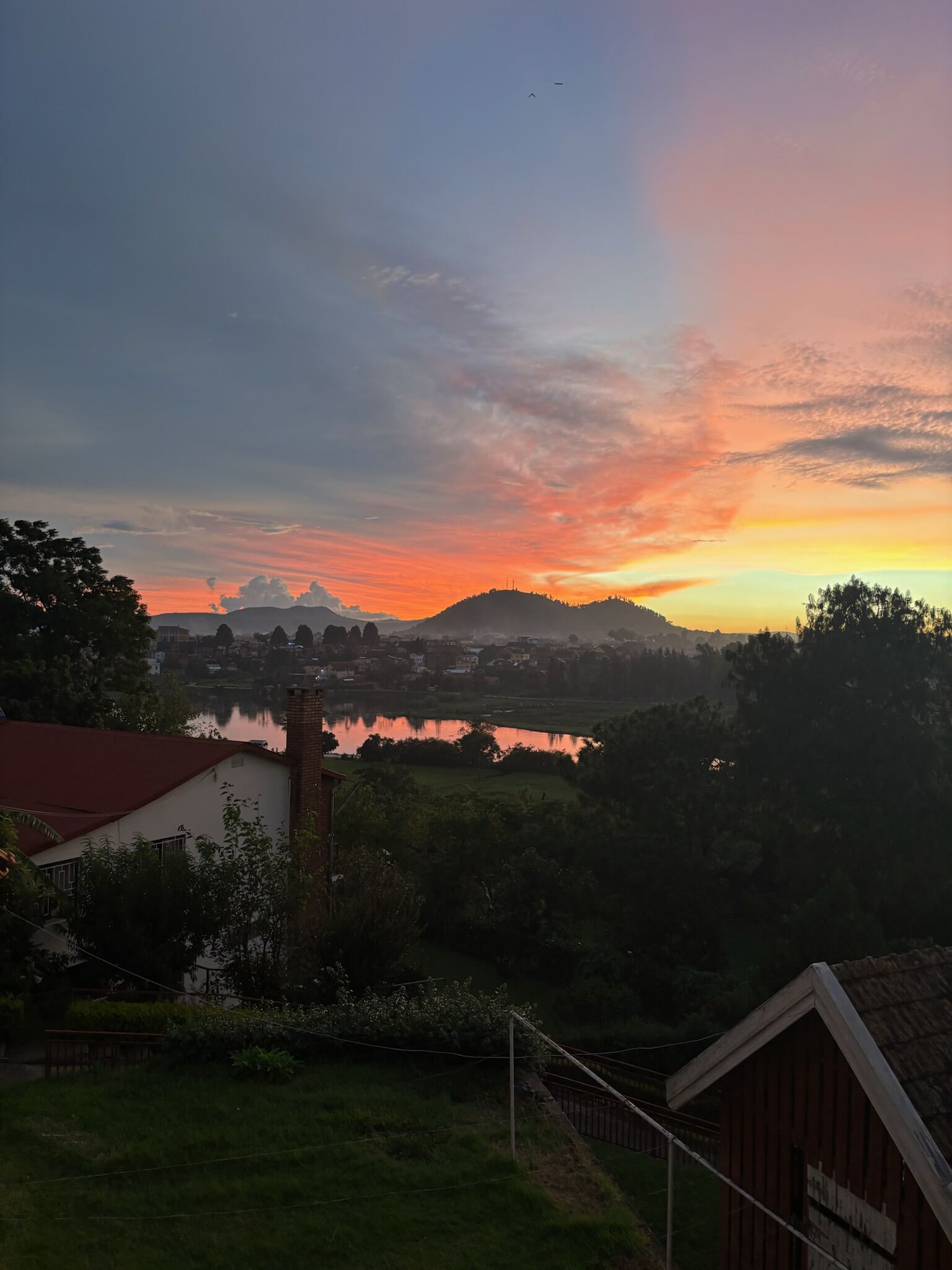 solnedgang rødt blått gult utsikt vann hustak skog